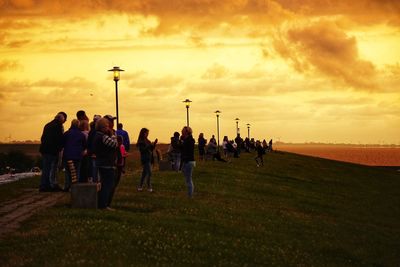 People on field against sky during sunset