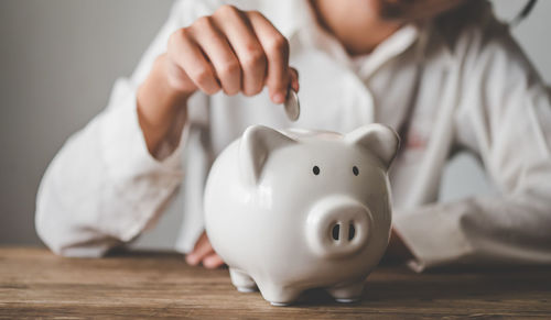 Midsection of woman holding piggy bank on table