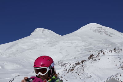 Person wearing ski-wear while photographing against snowcapped mountains