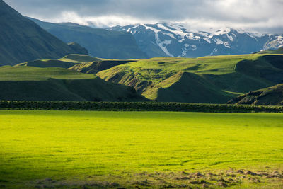 Scenic view of green landscape and mountains against sky