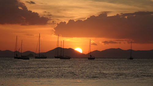 Silhouette sailboats in sea against sky during sunset