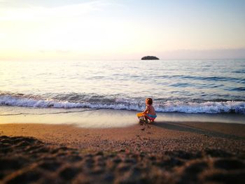Man on beach against sky during sunset