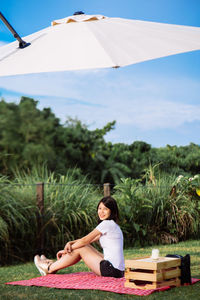 Woman sitting on rock against trees