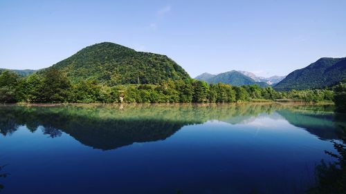 Scenic view of lake and mountains against blue sky