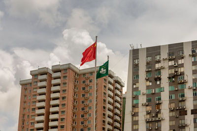 Low angle view of flag amidst buildings against sky