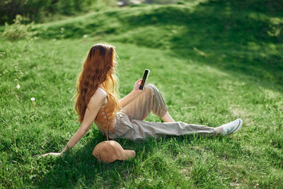 Rear view of woman sitting on grassy field