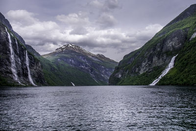 Scenic view of sea by mountains against sky