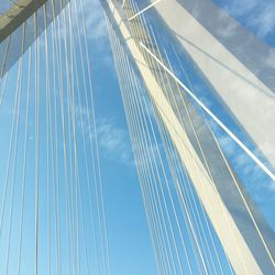 Low angle view of bridge cables against blue sky