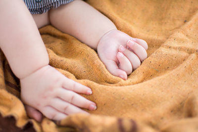Cropped hand of baby on blanket