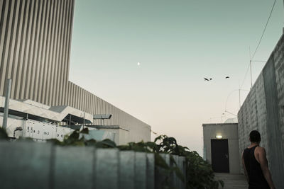 Rear view of man flying against sky in city