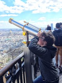 Side view of boy looking through hand-held telescope