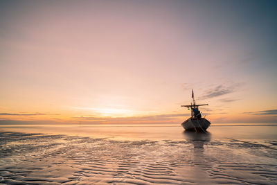 Silhouette ship in sea against sky during sunset