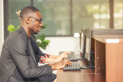 A black man works on a tablet computer in the hotel lobby.