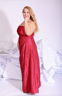 Side view portrait of beautiful young woman in red evening dress against white background