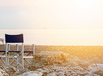 Chair on beach against sky