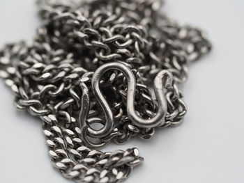 Close-up of metal chain on table against white background
