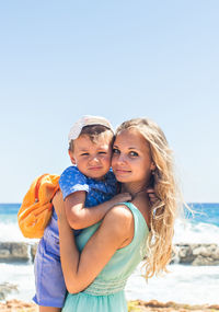 Portrait of mother and daughter against sky