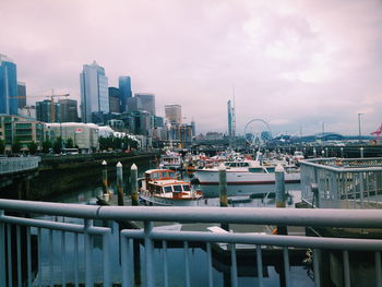 Bridge over river by buildings in city against sky