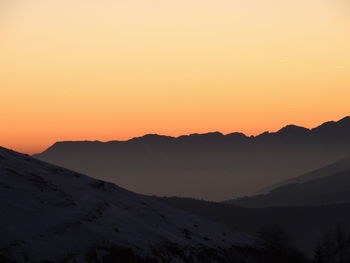 Scenic view of silhouette mountains against clear sky during sunset