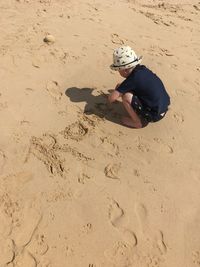 High angle view of boy writing on sand at beach