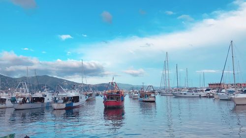 Sailboats moored in sea against sky