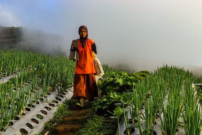 Woman standing on field against sky