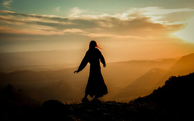 Side view of man standing on mountain against sky during sunset