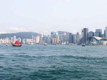 Sea and buildings in city against clear sky