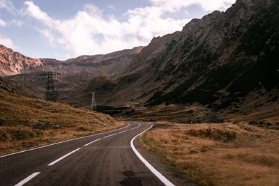 Road leading towards mountains against sky