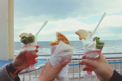 People holding ice cream against sky