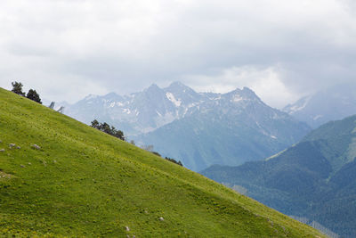 Green slope of a high mountain during a thunderstorm with clouds in the sky