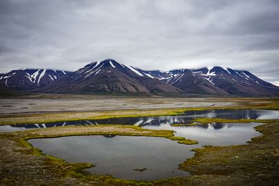 Scenic view of lake and snowcapped mountains against sky summer in longyearbyen spitzbergen 