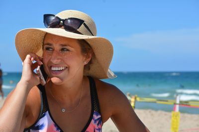 Smiling young woman talking on mobile phone at beach