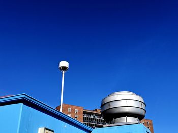 Low angle view of street light against building against clear blue sky