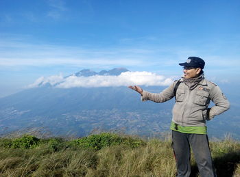 Optical illusion of man holding cloud while standing on mountain