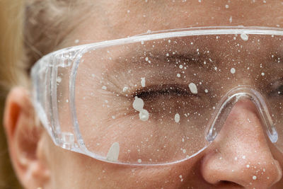 Close up of a smiling woman face wearing protective glasses covered in paint