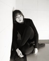 Portrait of a young woman sitting on tiled floor