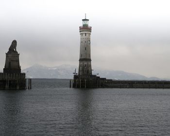 Lighthouse by mountain against sky