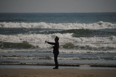 Full length of man standing at beach against sky