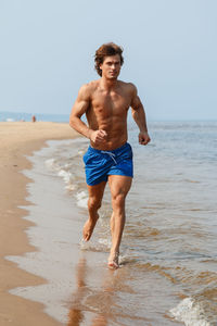 Portrait of shirtless man standing at beach