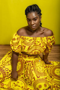 Young beautiful woman, serious, looking at the camera, sitting on a wooden floor. 