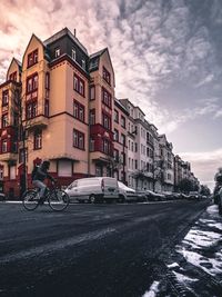 Bicycle parked on road by buildings against sky