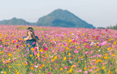 Portrait of woman standing amidst blooming flowers