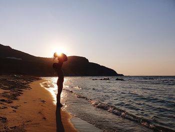 Silhouette person on beach against sky during sunset