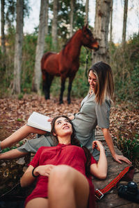 Woman smiling while sitting on land in forest