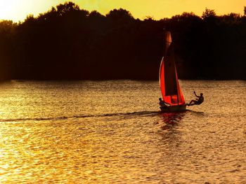 Man on boat in lake against sky during sunset