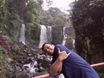 Portrait of man against waterfall in forest