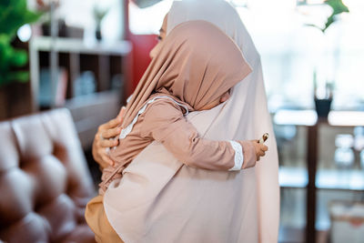 Side view of mother embracing baby wearing hijab