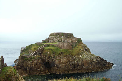 Rock formations by sea against sky