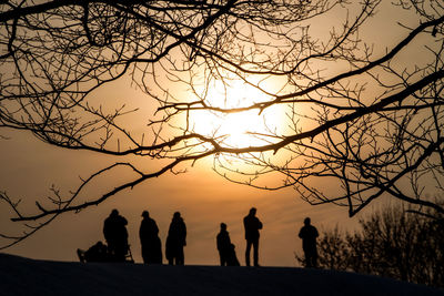 Silhouette people standing on mountain against sky during sunset